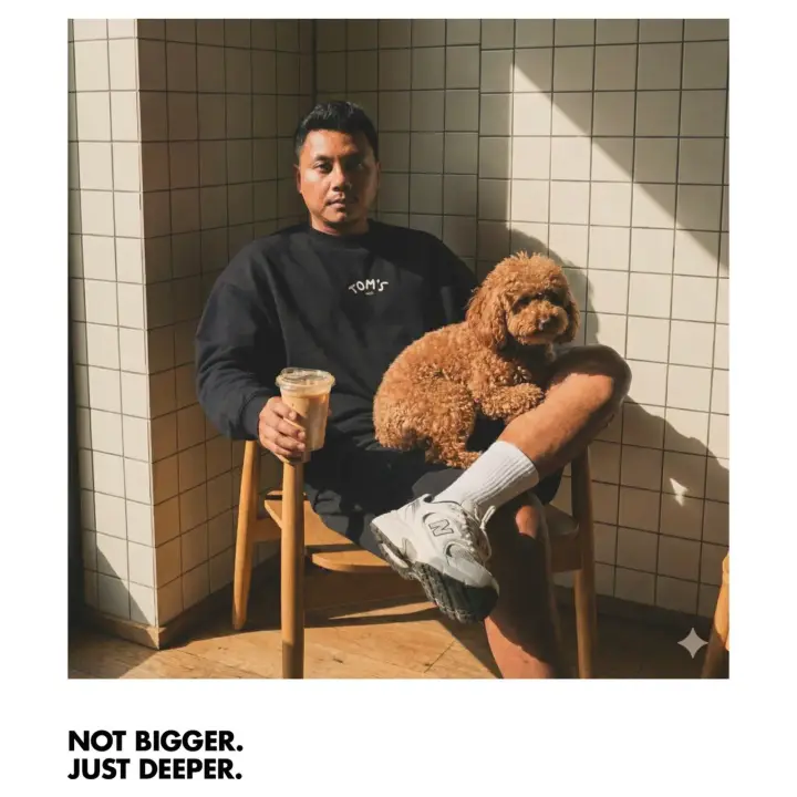 A guest in a TOM'S sweatshirt with a poodle and an iced coffee