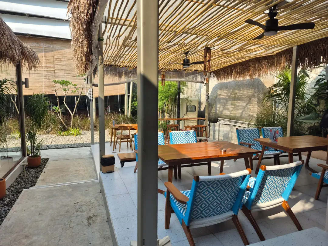 Terrace with blue rattan chairs under a bamboo canopy