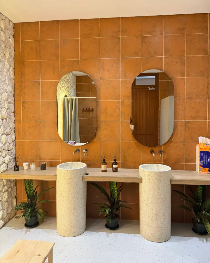 Terracotta-tiled bathroom with round mirrors